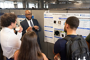 Students gathered around a research poster presentation