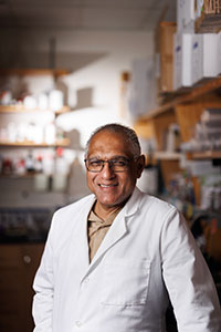 Soman Abraham, BS, MS, PhD, in lab coat in lab