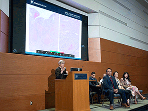 Dr. Maria Angelica Selim at podium in front of presentation screen