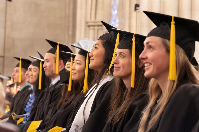 Students in Graduation regalia sitting in a row.