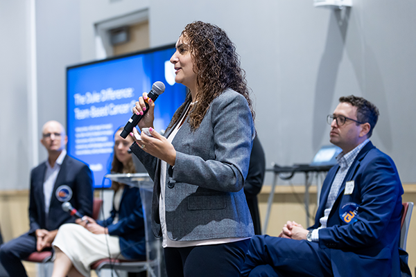 Dr. Diana Kozman talks to a patient audience, holding up a pathology slide to help them visualize the role that pathologists play in diagnosing cancers