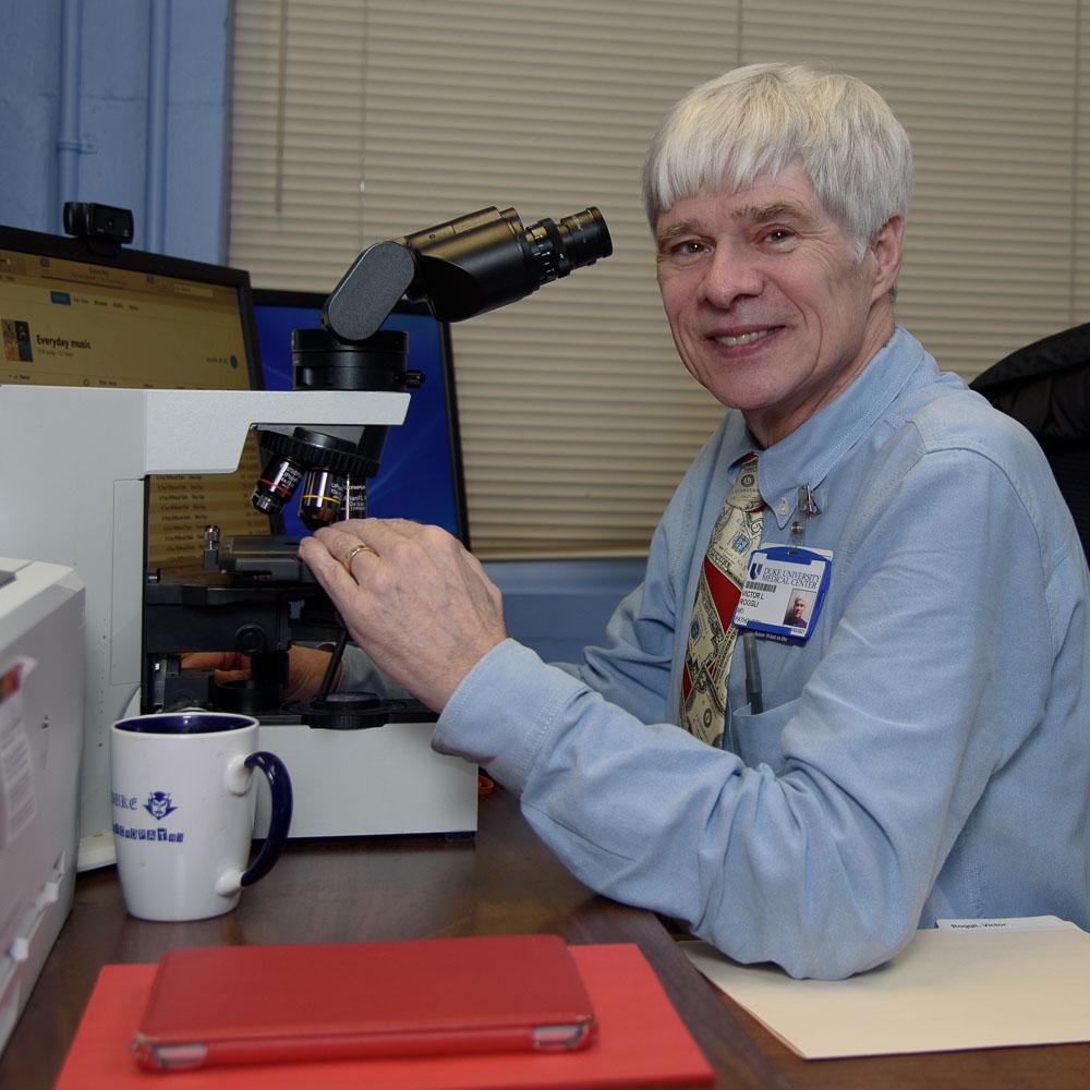 Dr. Victor Roggli at microscope at his desk