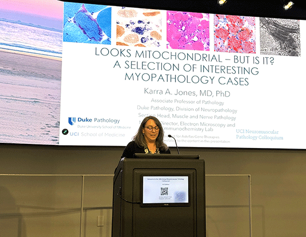 Dr. Karra Jones speaking in front of screen with title "Looks Mitochondrial-But is it? A selection of interesting myopathology cases"